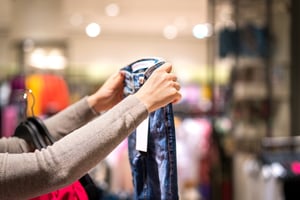 woman holding jeans in a shop